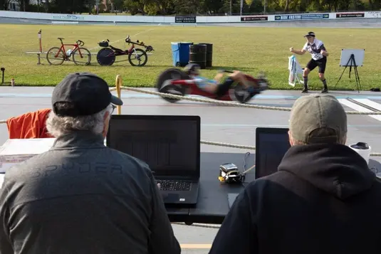 Motion-blurred recumbent bicycle racer speeding past the coaches