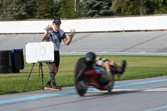 Motion-blurred recumbent bicycle racer speeding passing by the coach