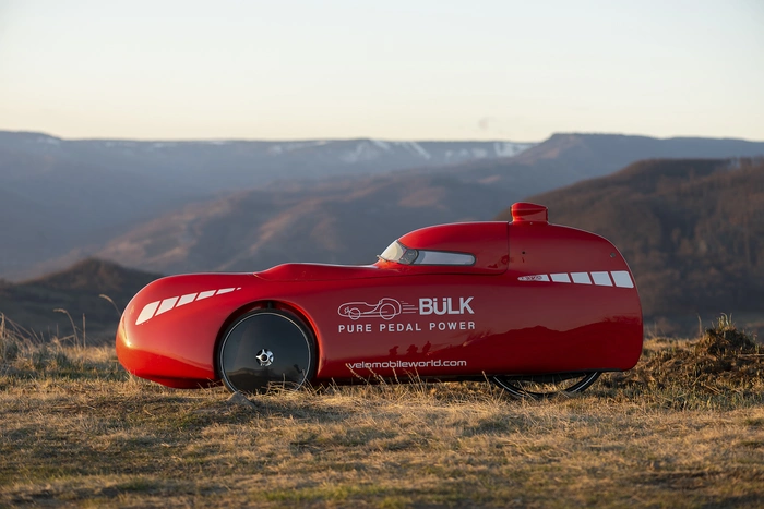 A red Bülk urban velomobile in rural environments